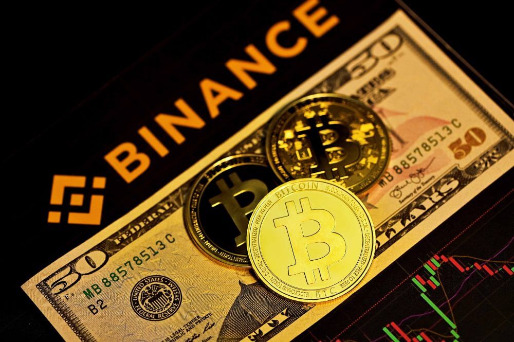 Bitcoin coins, a fifty dollar bill, and Binance crypto exchange.