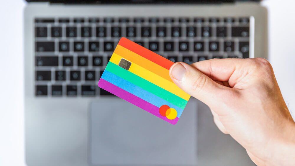 Rainbow coloured credit / debit card and laptop. 