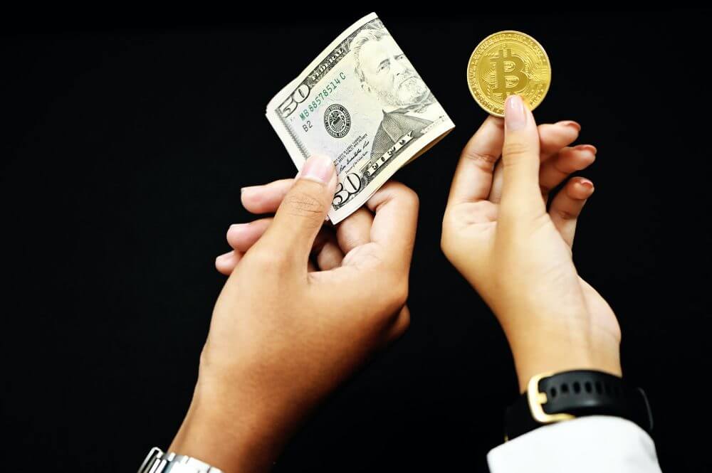 Hands holding US dollars and bitcoin