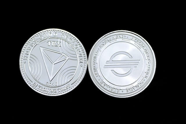 Tron (TRX) and Stellar Lumens (XLM) cryptocurrencies, represented by physical coins.