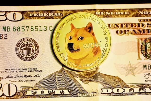 Dogecoin cryptocurrency, represented by a physical coin lying on a 50 dollar bill. 