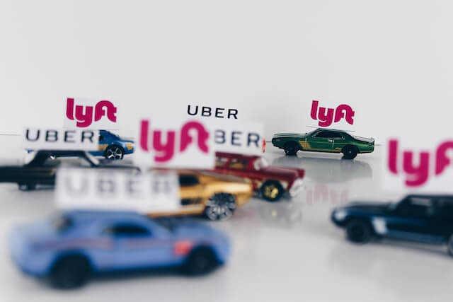 Uber and Lyft represented by toy cars. 
